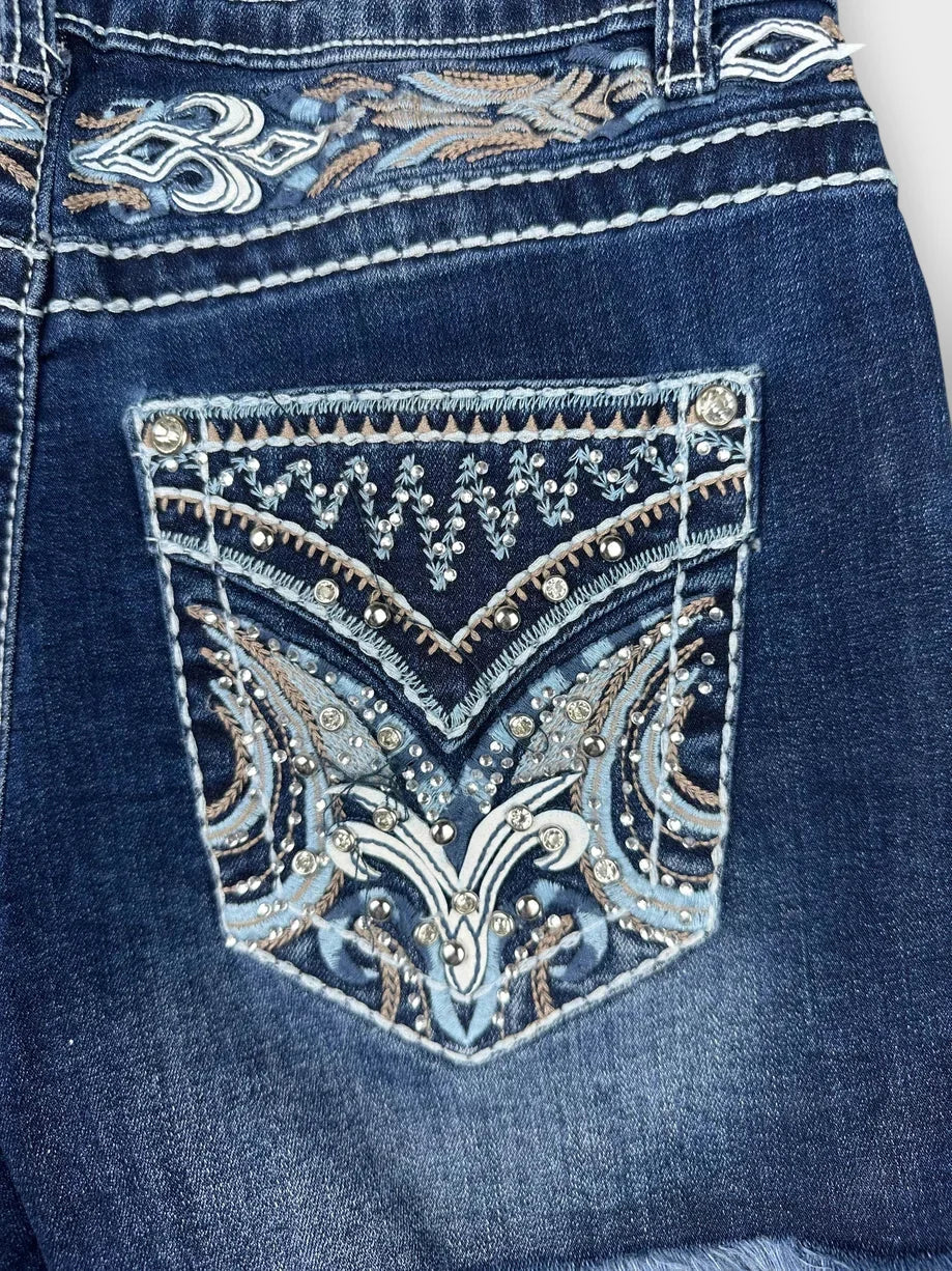 Detail view of distressed denim mini shorts with intricate blue embroidery.