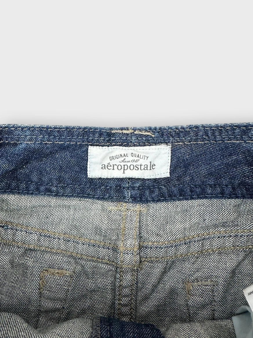 Detail view of distressed denim mini skirt in navy blue with frayed hem.