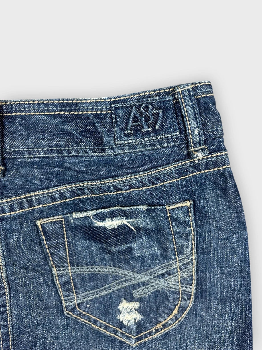 Detail view of distressed denim mini skirt in navy blue with frayed hem.