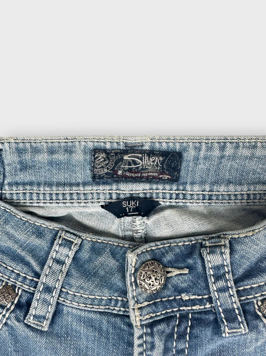 Light blue denim jeans with silver button detail view.
