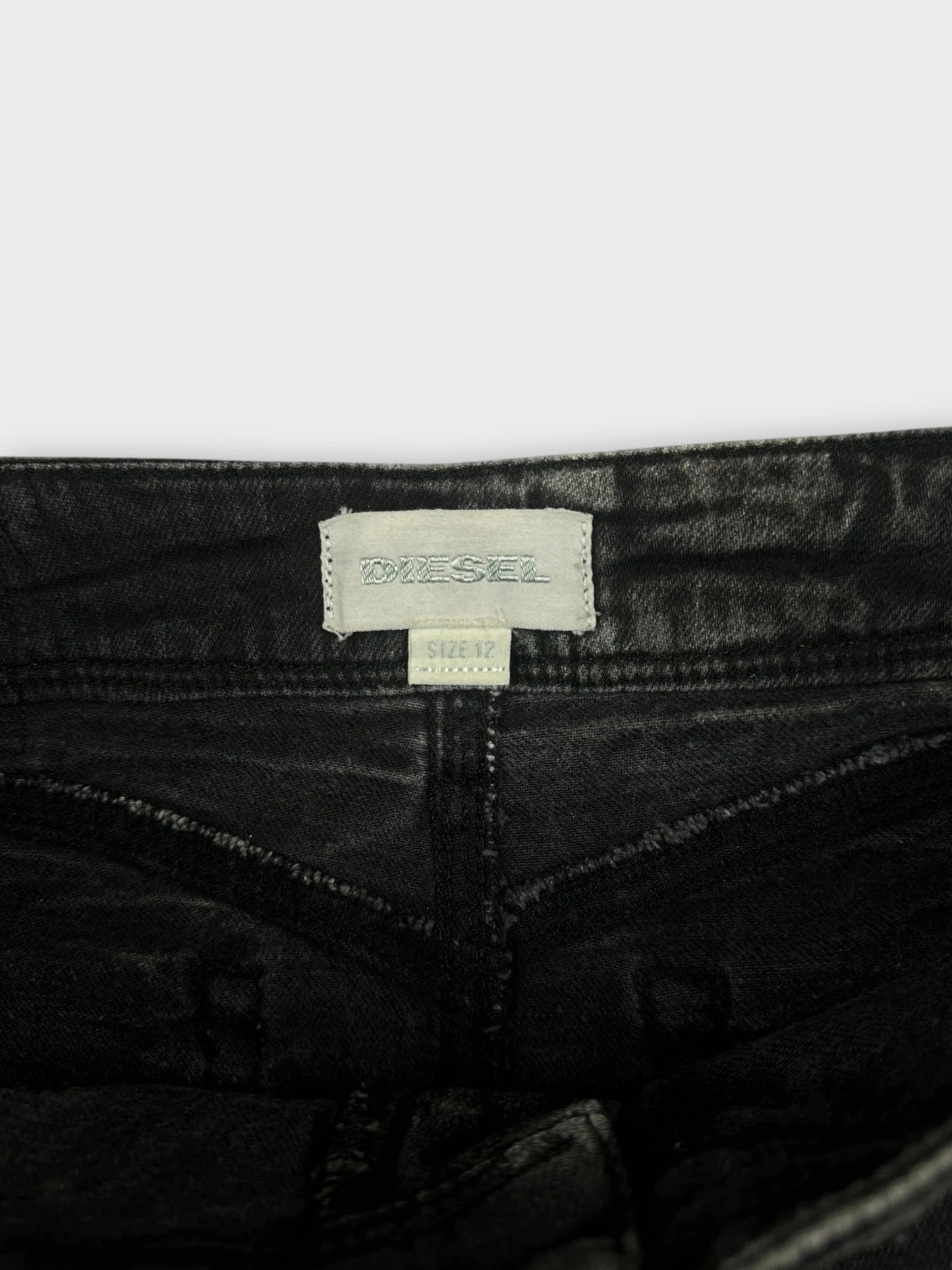 Detail view of a black denim mini skirt with visible brand tag and waistband stitching.