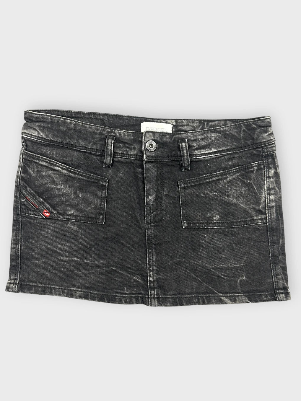 Edgy black denim mini skirt front view featuring front pockets and a distressed finish.