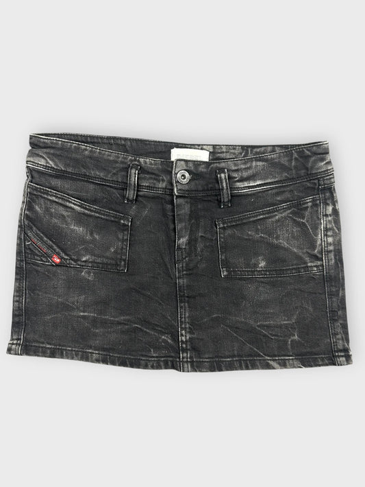 Edgy black denim mini skirt front view featuring front pockets and a distressed finish.