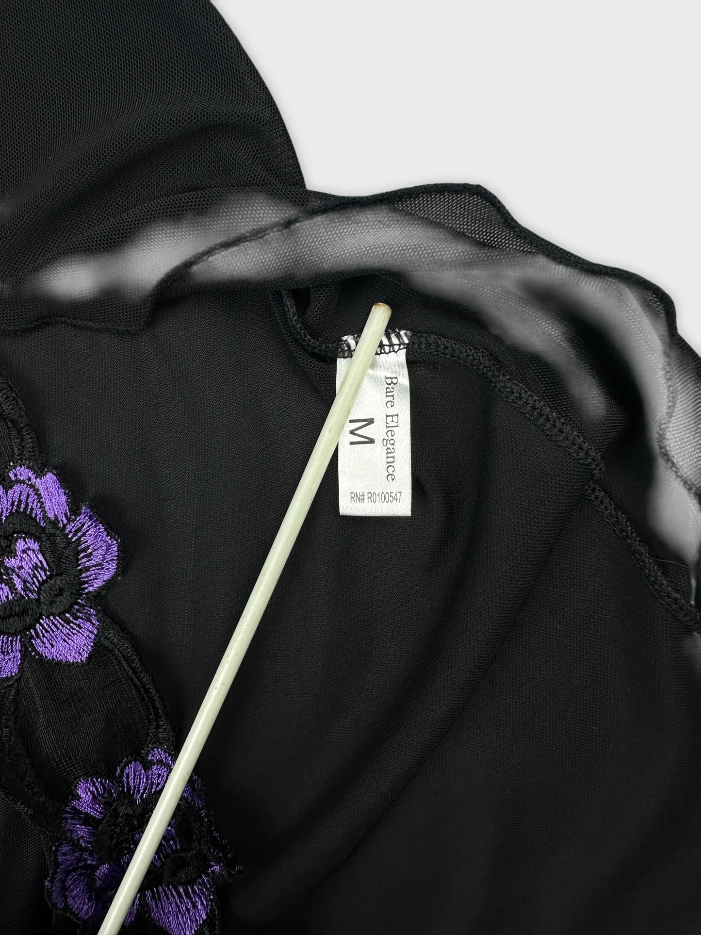 Detail view of a black mesh tank top with purple floral embroidery
