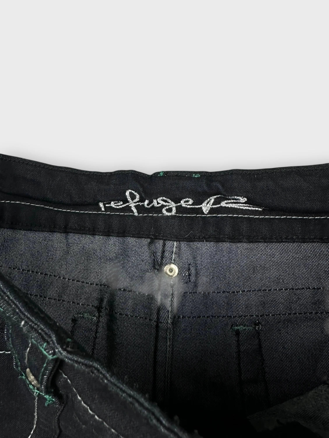 Detail view of an outline of a black mini skirt with pockets.