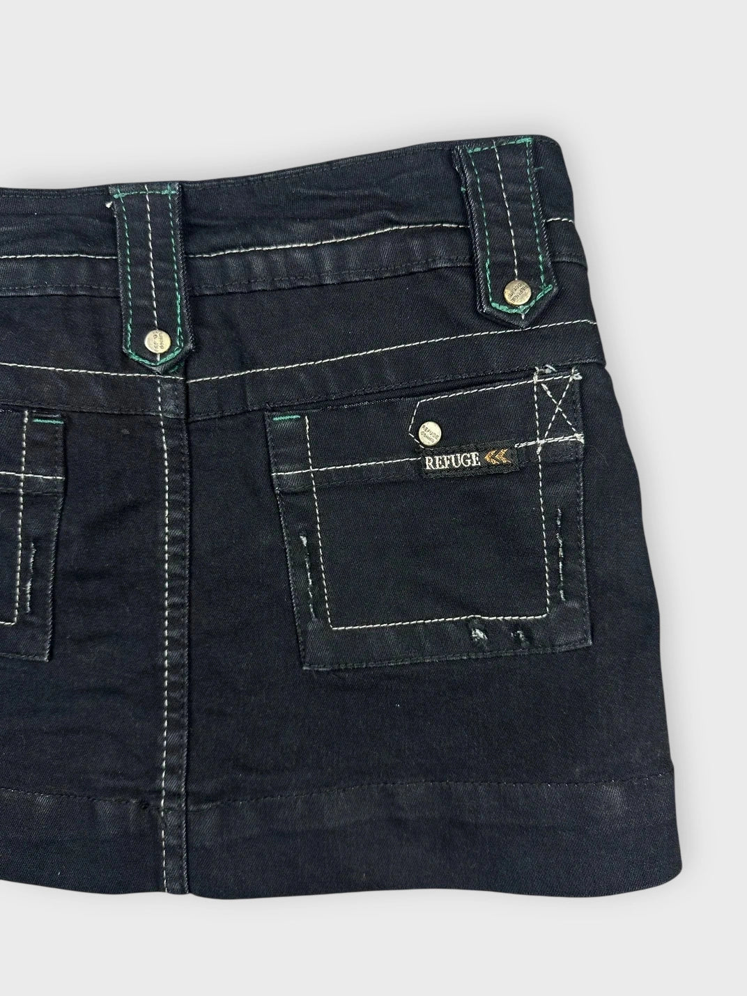 Detail view of black mini skirt featuring pockets and contrasting stitching.