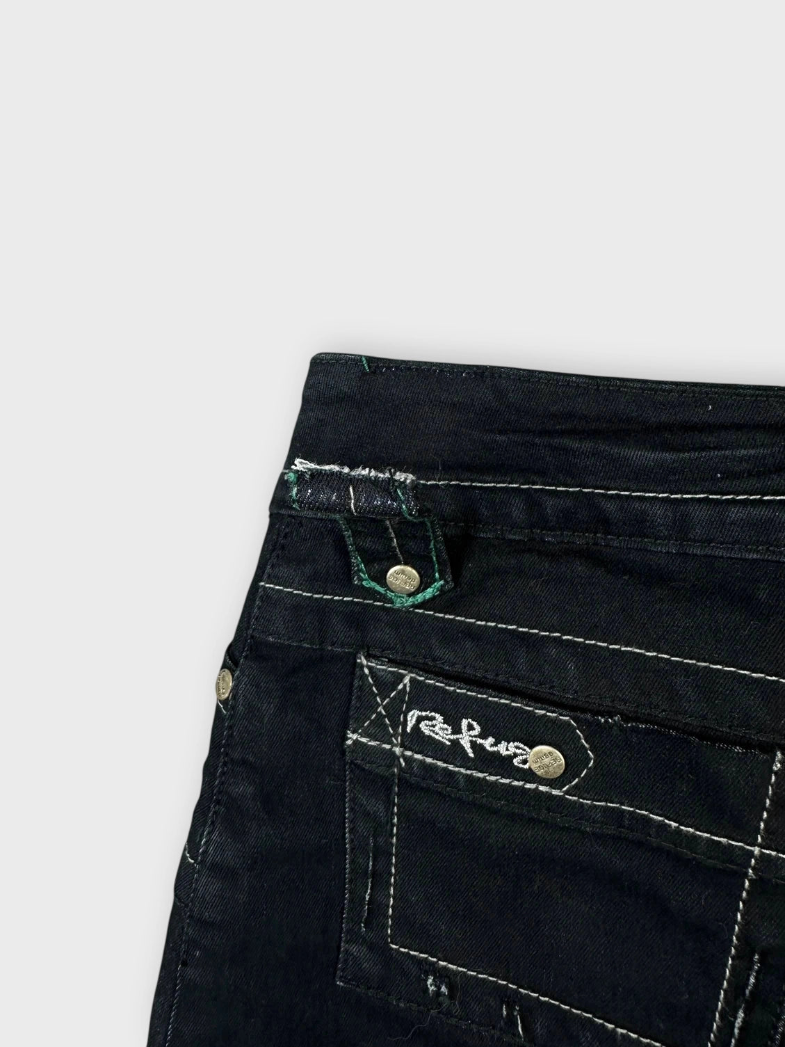 Detail view of a black mini skirt featuring visible pockets and stitching.