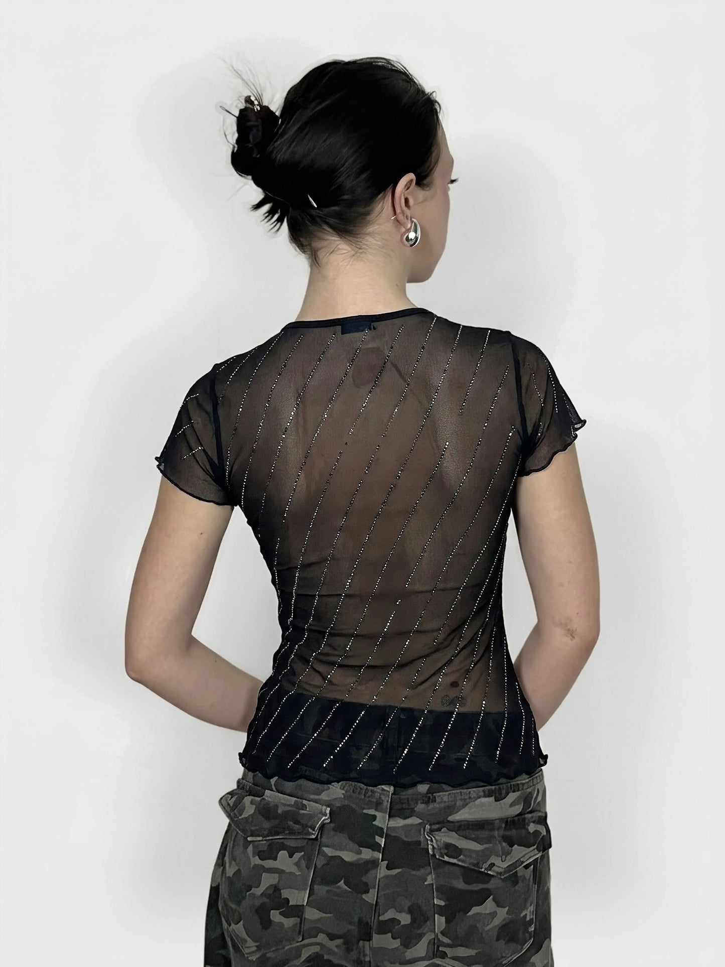Back view of a black shimmer top with ruffles and diagonal sparkly lines.