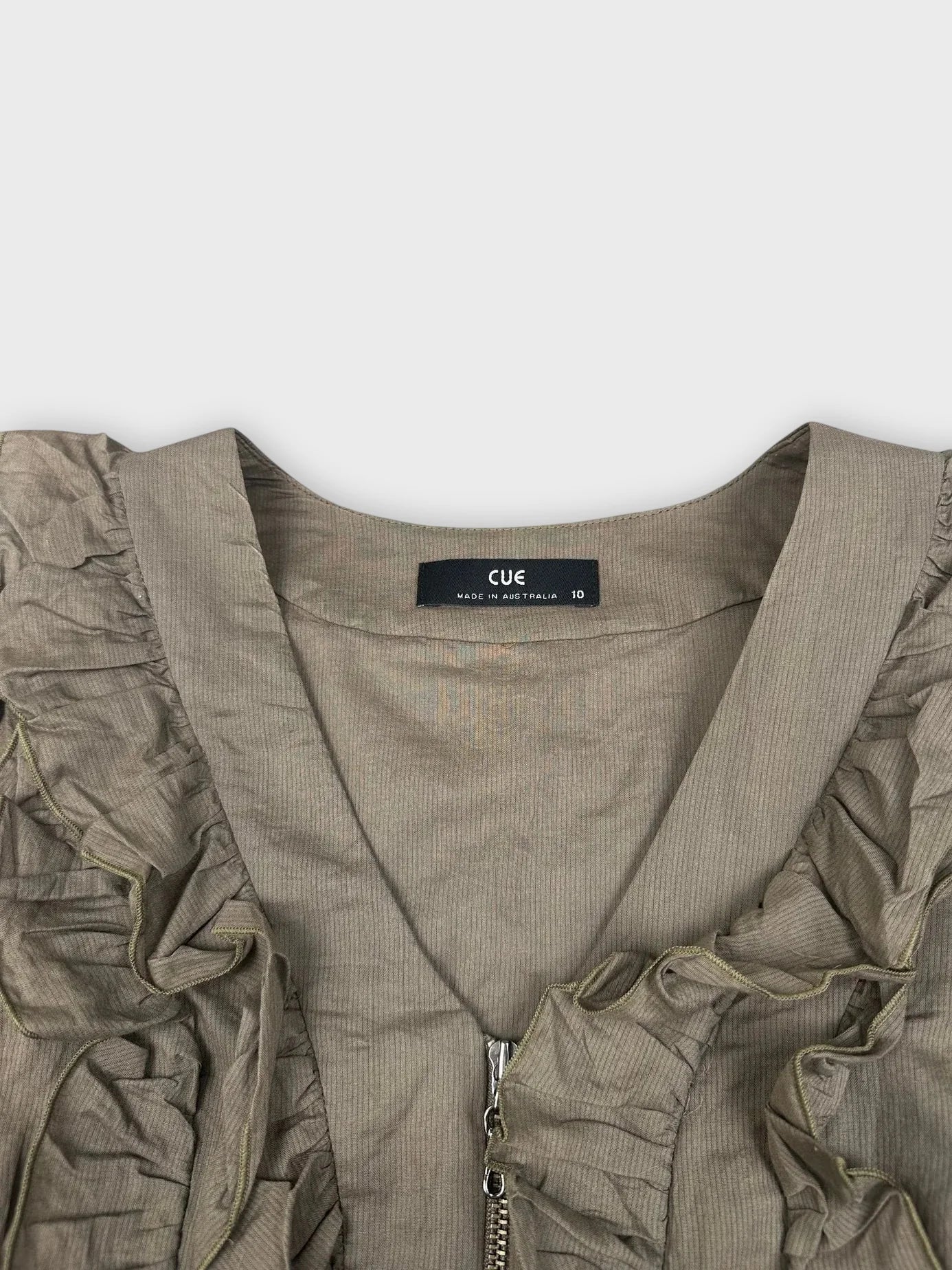 Detail view of a green ruffle zip top with textured trim.