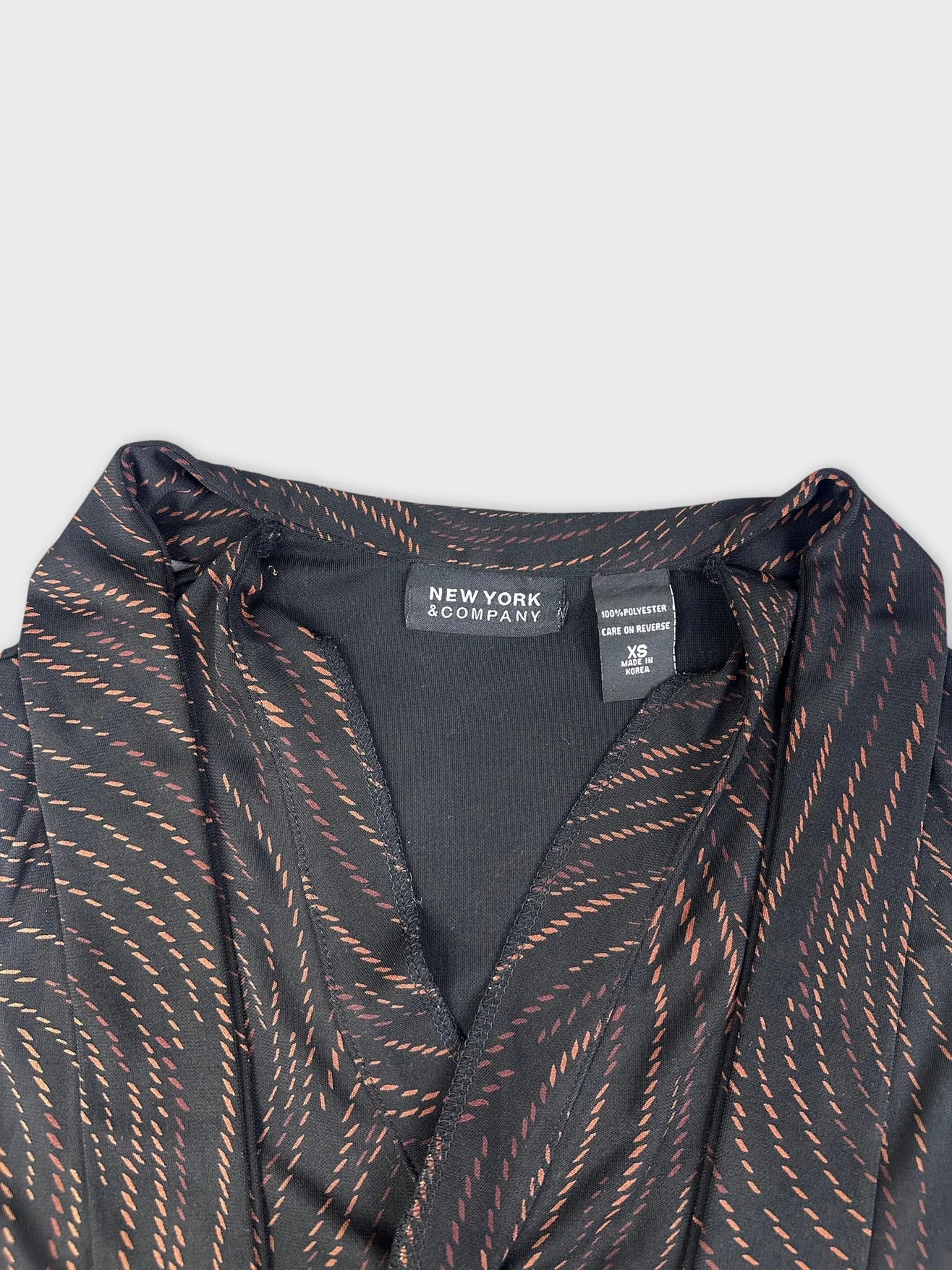 Detail view of elegant black cowl neck top featuring swirl pattern.
