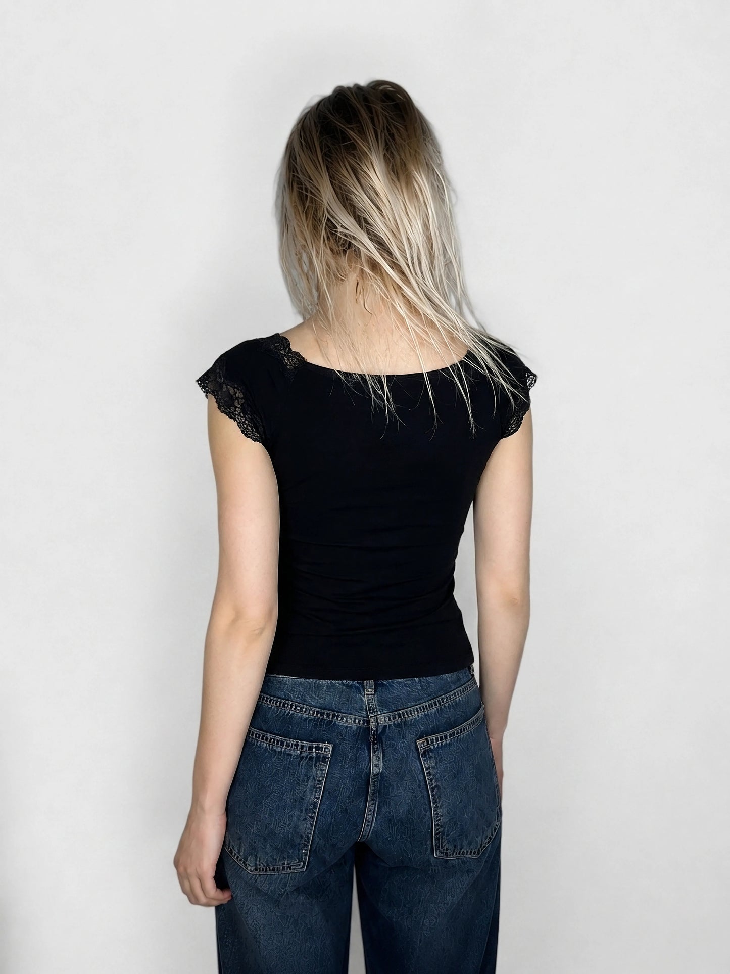 Back view of a black top featuring lace trim on shoulders.