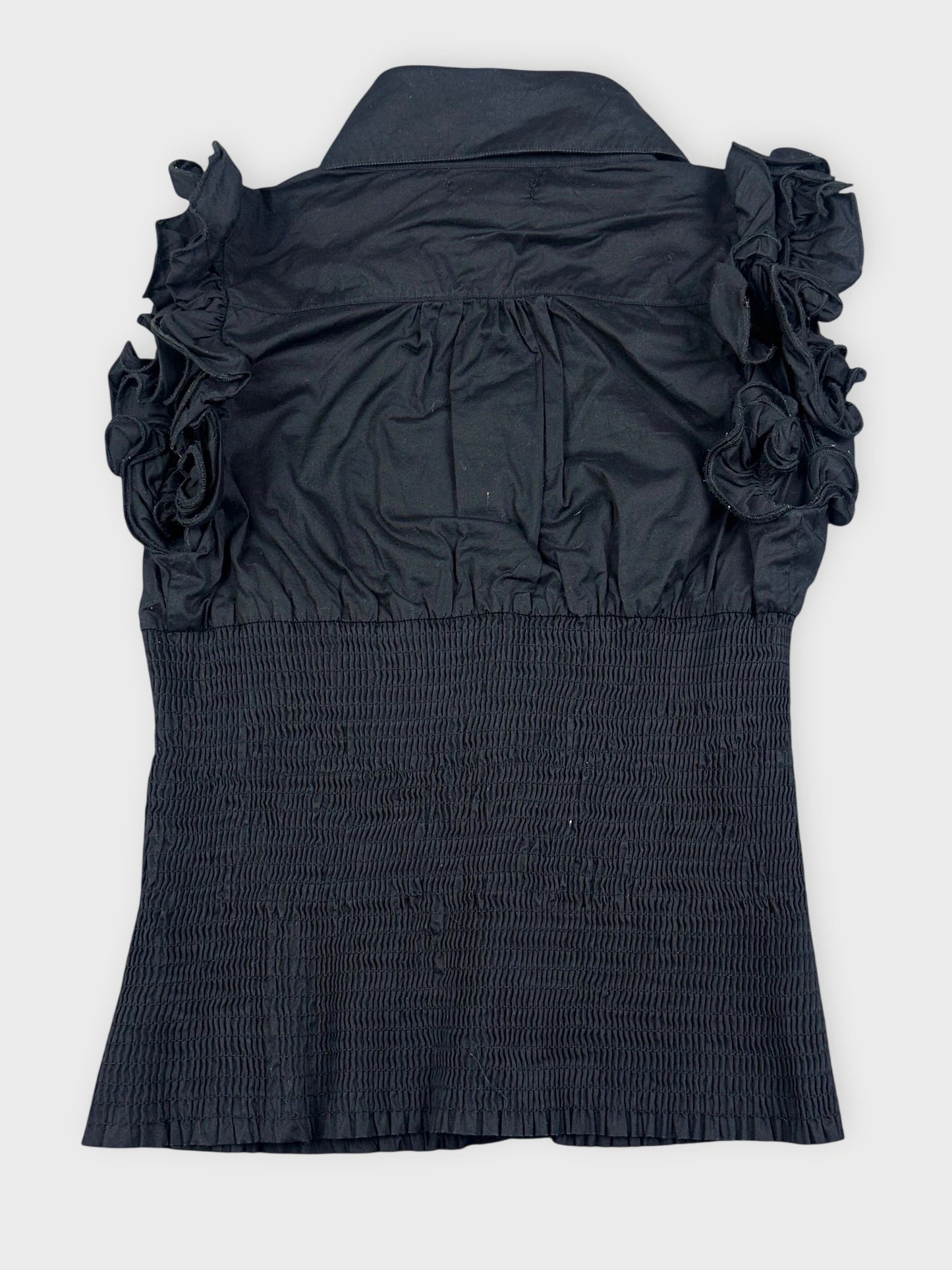 Back view of a black ruffled blouse with button detail and smocked texture.