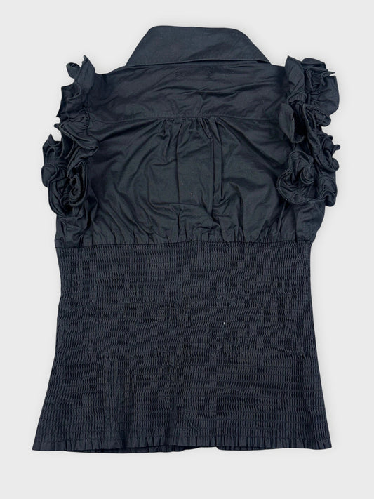 Back view of a black ruffled blouse with button detail and smocked texture.