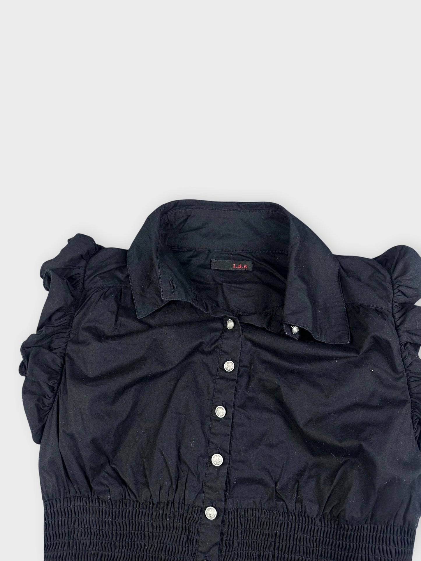 Detail view of a black ruffled blouse with button closure.
