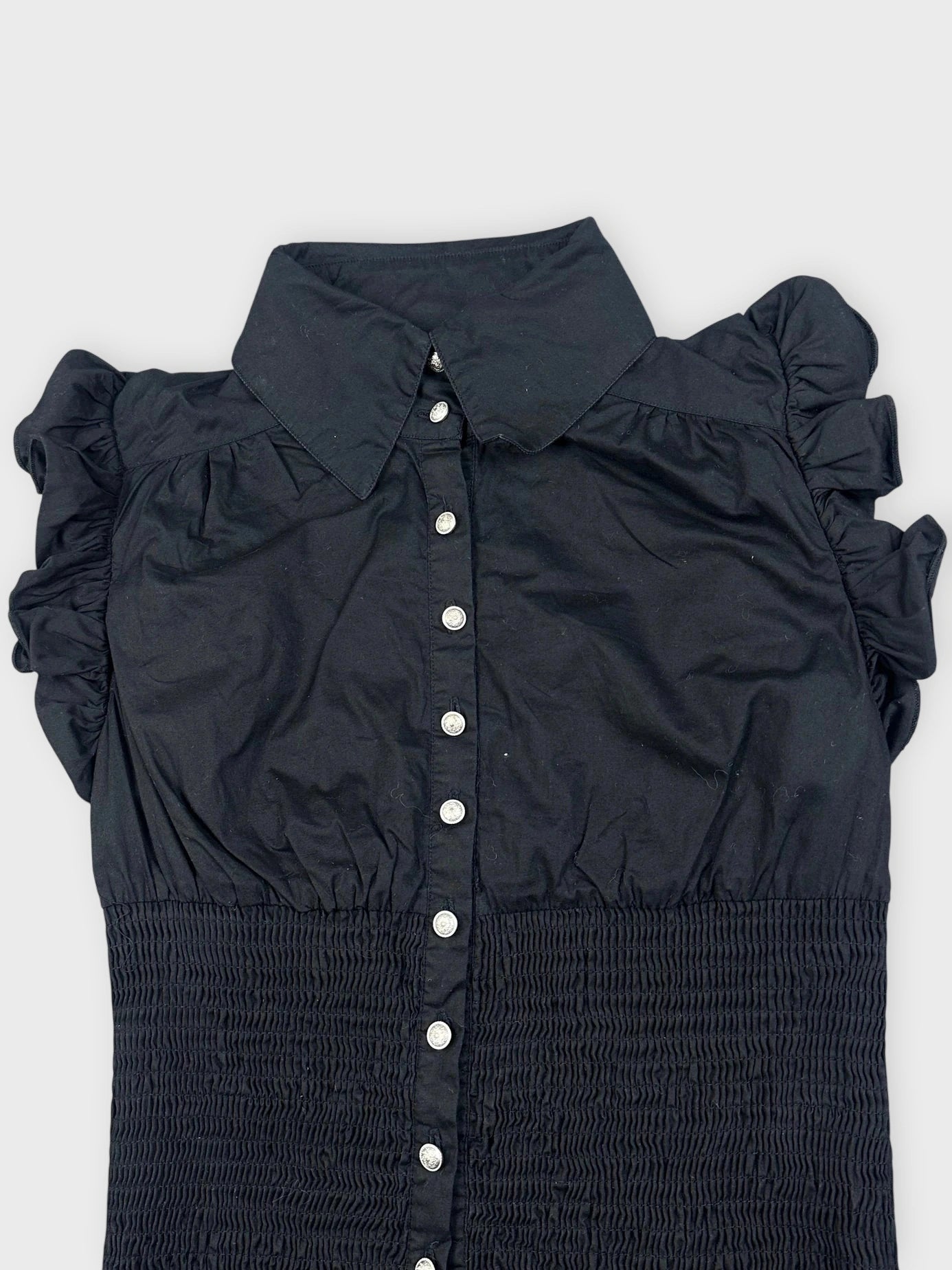 Detail view of a black ruffled blouse featuring button closure.