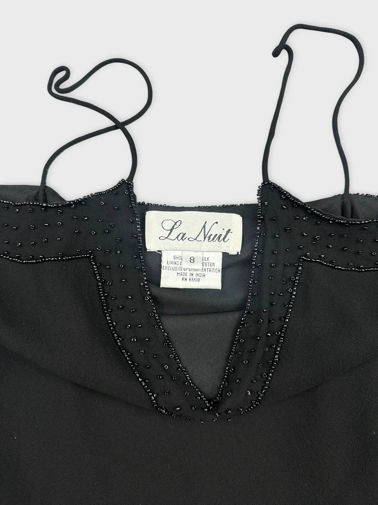 Detail view of black silk camisole featuring lace trim and beaded neckline.