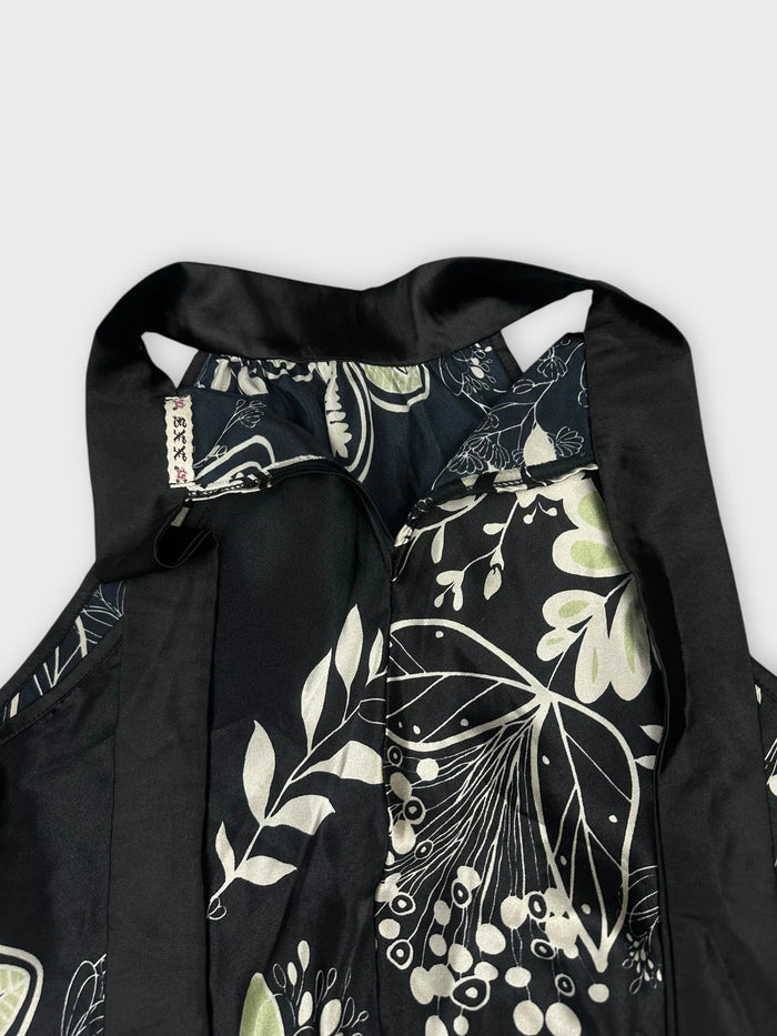 Detail view of floral halter top in black with green botanical print.