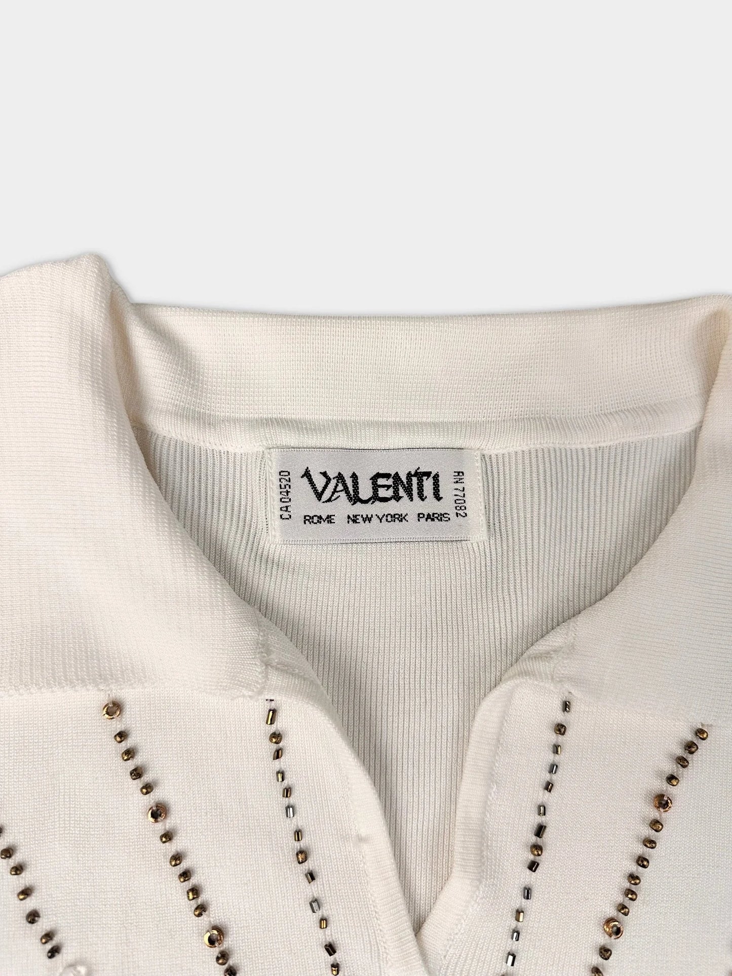 Detail view of an elegant sleeveless top in off-white with beaded details.