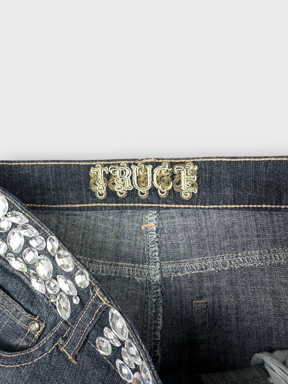 Detail view of a dark blue denim mini skirt with embellishments.