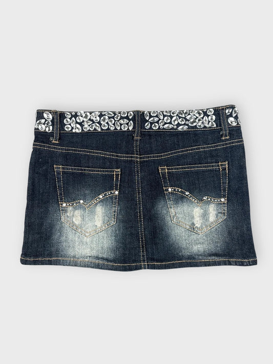 Detail view of a dark blue denim mini skirt with embellished waistband.