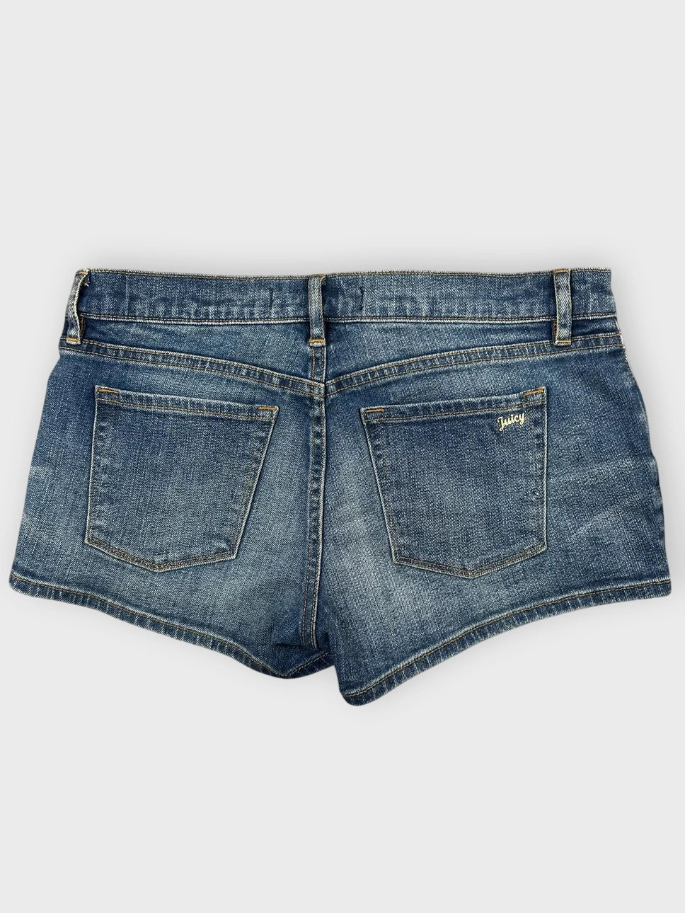 Back view of blue denim mini shorts featuring embroidered detail on pockets.
