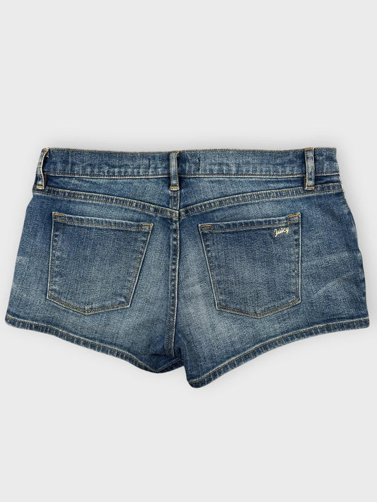 Back view of blue denim mini shorts featuring embroidered detail on pockets.