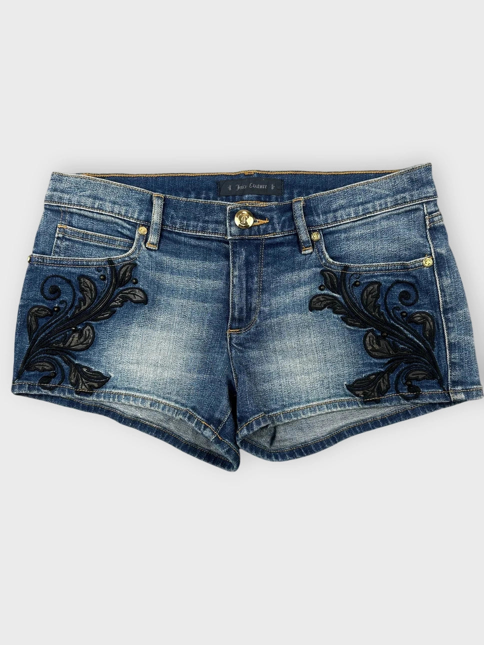 Embroidered denim mini shorts in light blue with black floral embroidery front view.