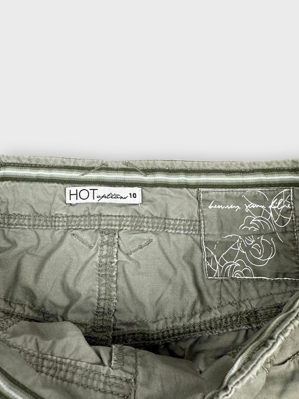 Detail view of faded green mini skirt with pocket details and stitching.