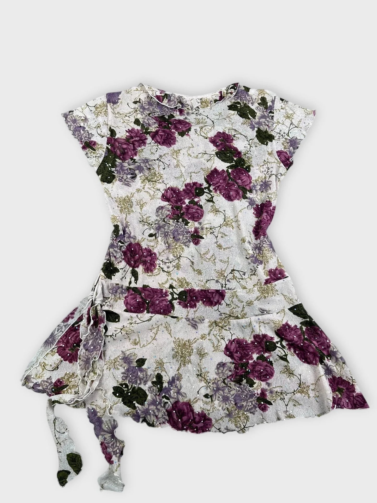 Back view of a floral mesh top in purple and white with ruffled trim.
