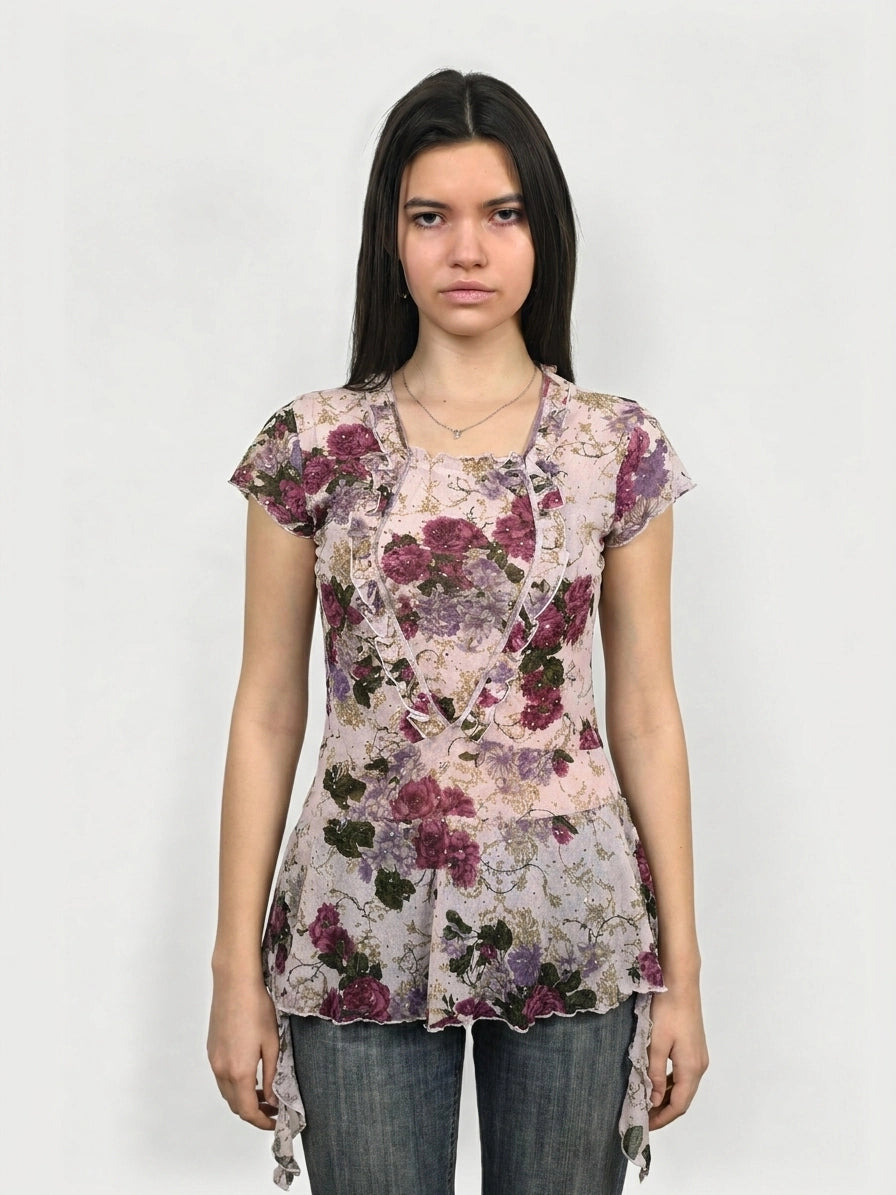 Front view of a floral mesh top in pink, featuring ruffled trim.