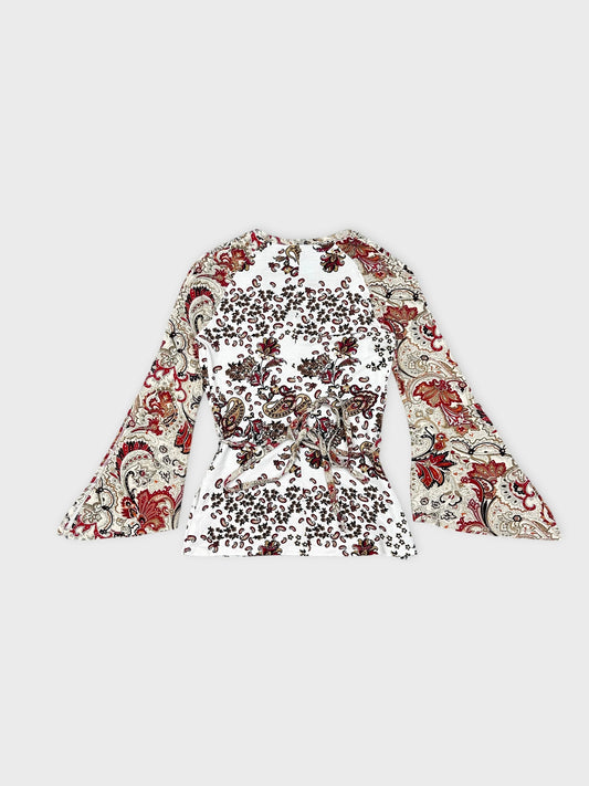 Back view of a long-sleeve white top with floral paisley print.