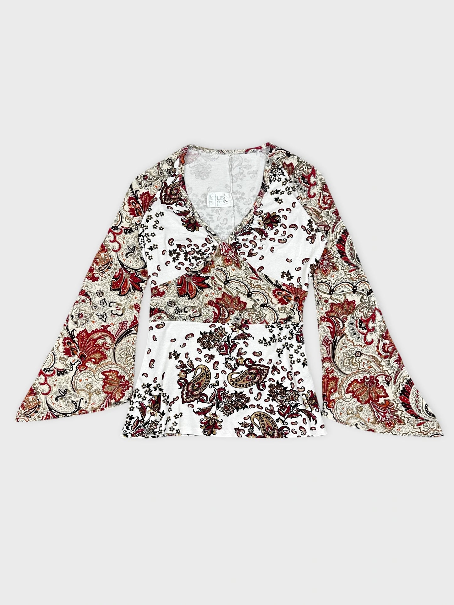 Detail view of a floral paisley print long-sleeve top in white and red.