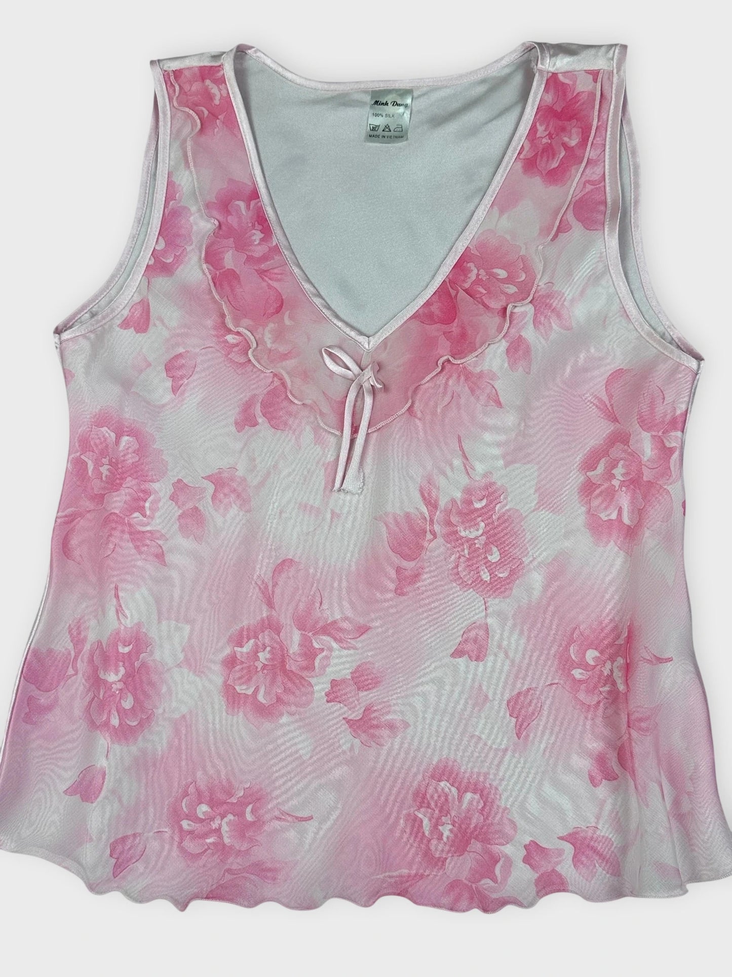 Detail view of pink floral silk sleeveless top with a tie detail.