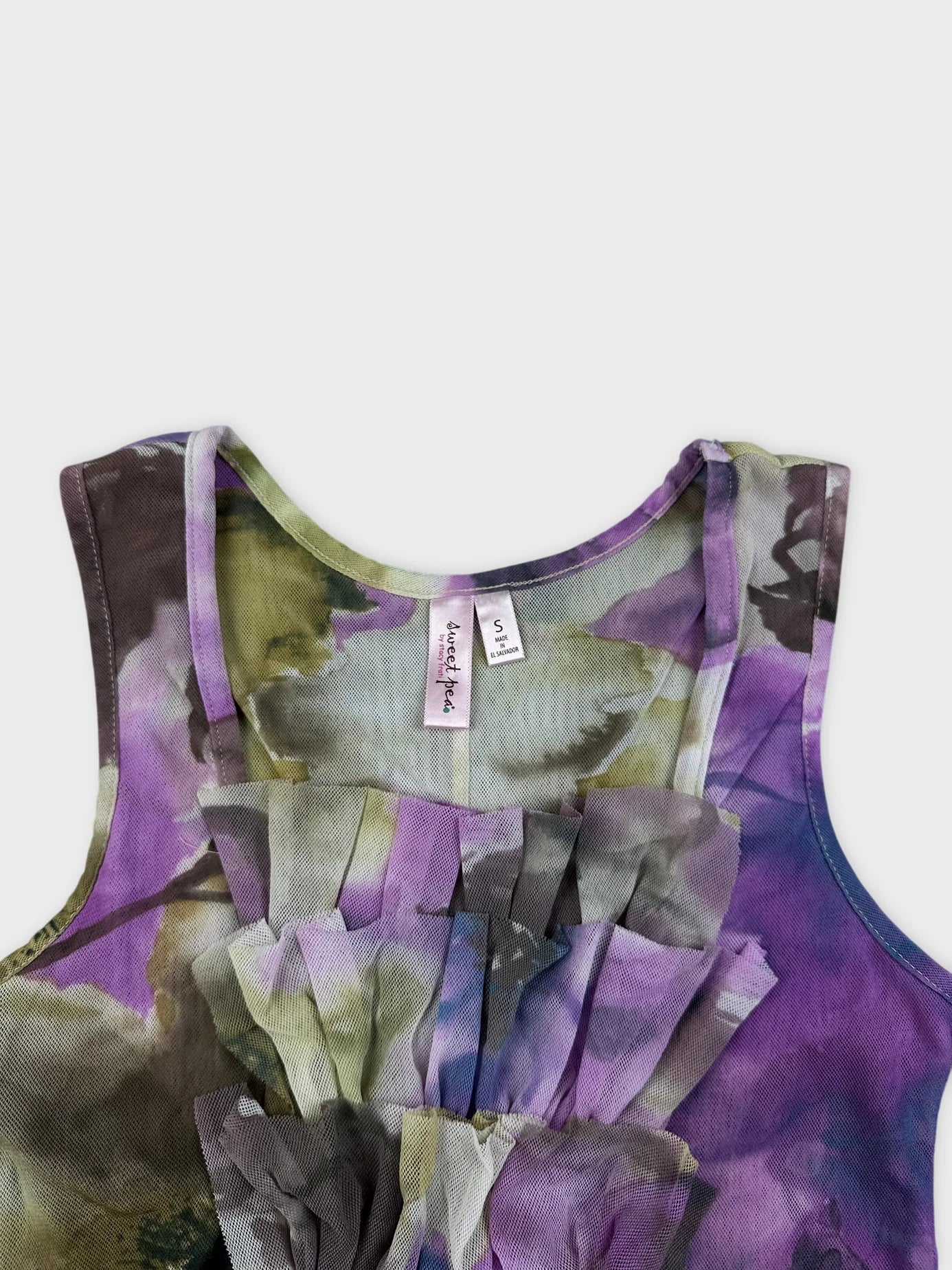 Detail view of a floral print sleeveless dress in purple with ruffled front.
