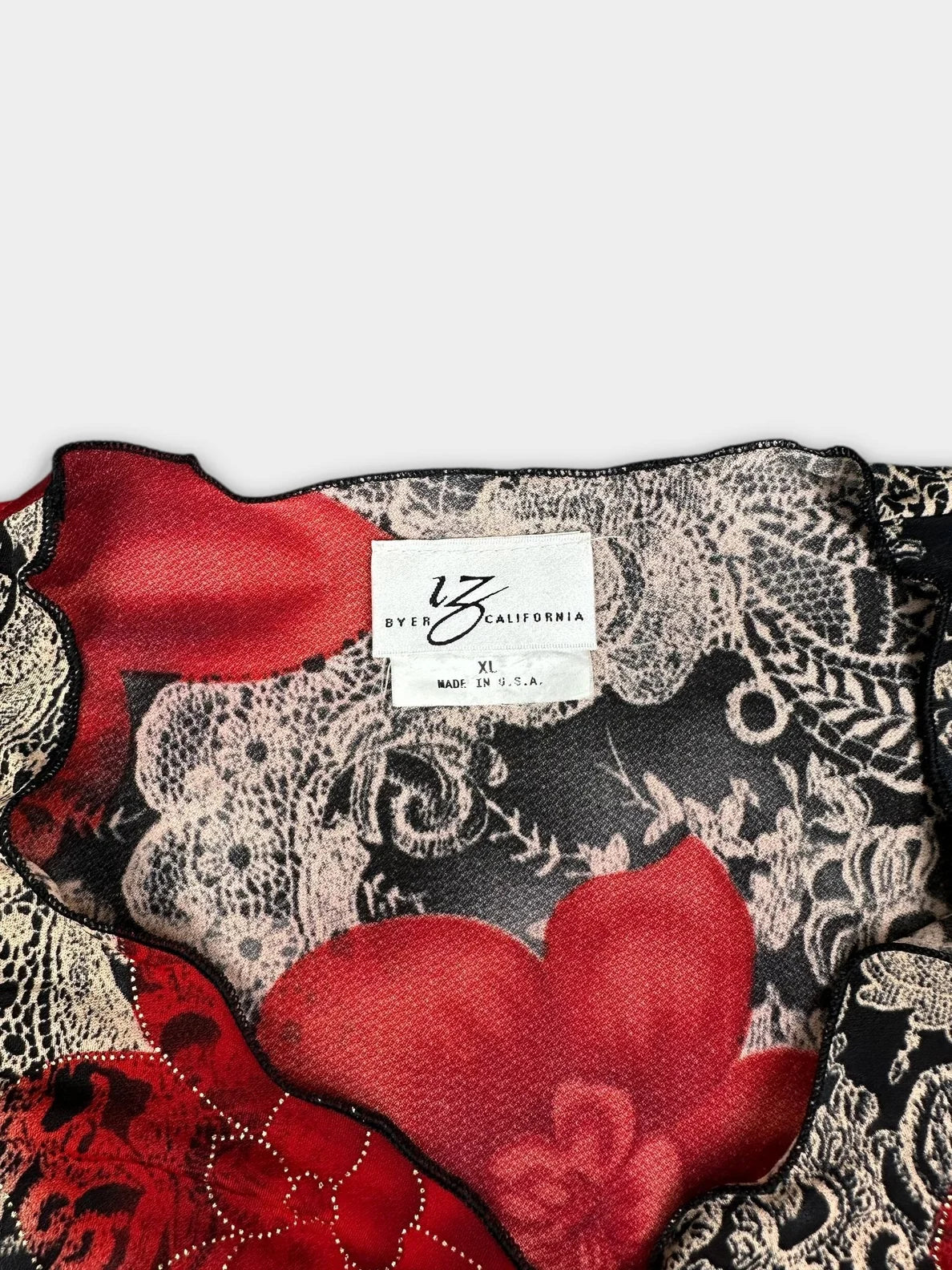Detail view of floral ruffle sleeve top in red and black with lace trim.
