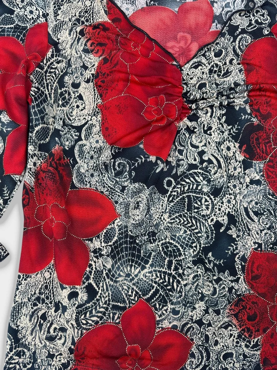 Detail view of floral ruffle sleeve top featuring red flowers on a black background.