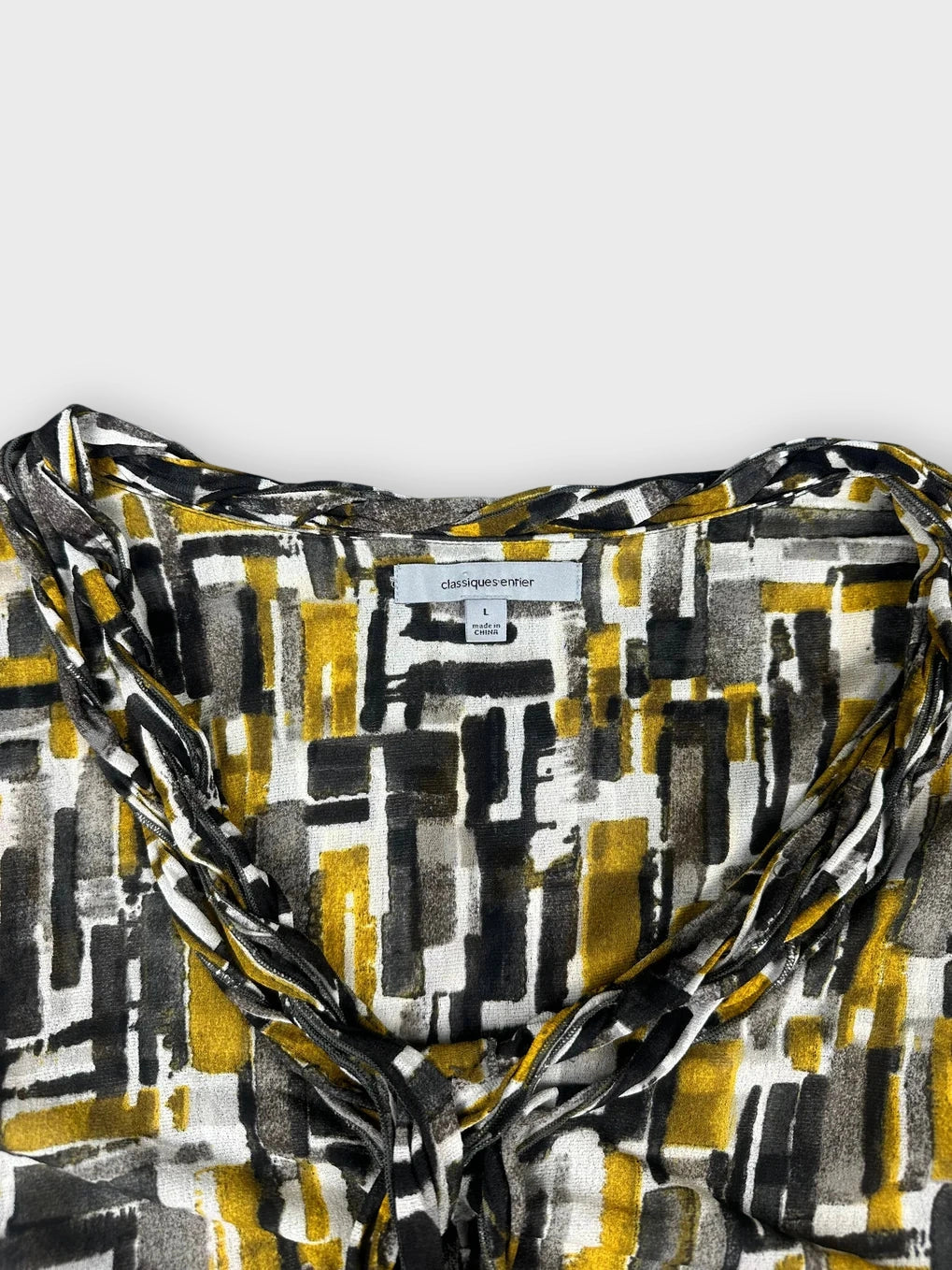 Detail view of a graphic print sleeveless top in yellow black and white with ruching.
