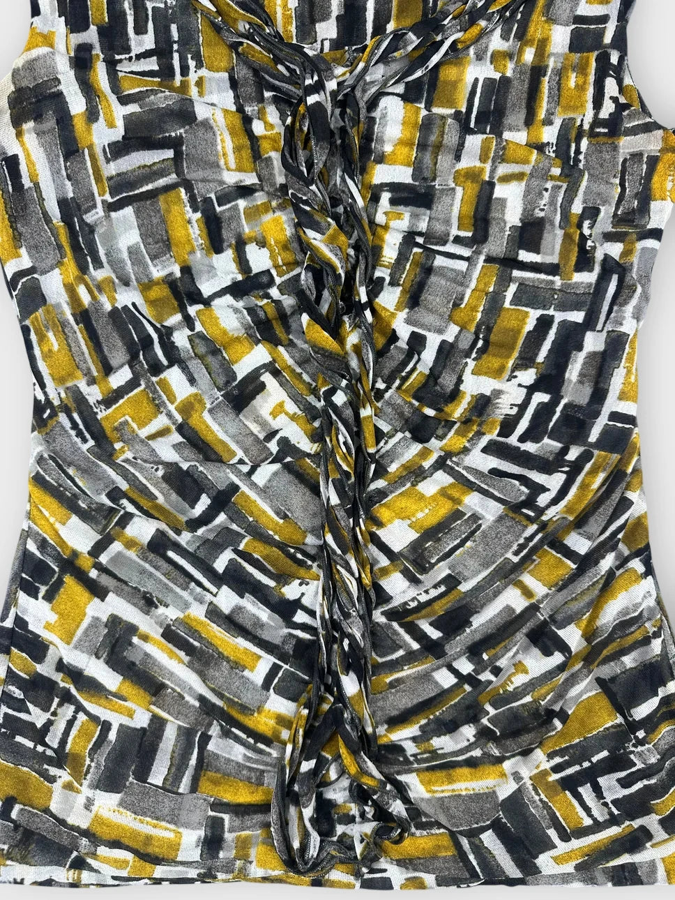 Detail view of sleeveless top with geometric print in black and yellow