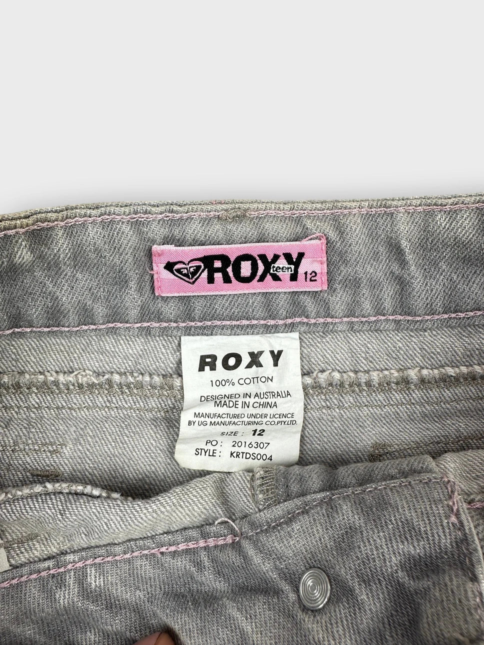 Detail view of a grey denim mini skirt with embroidered hem.