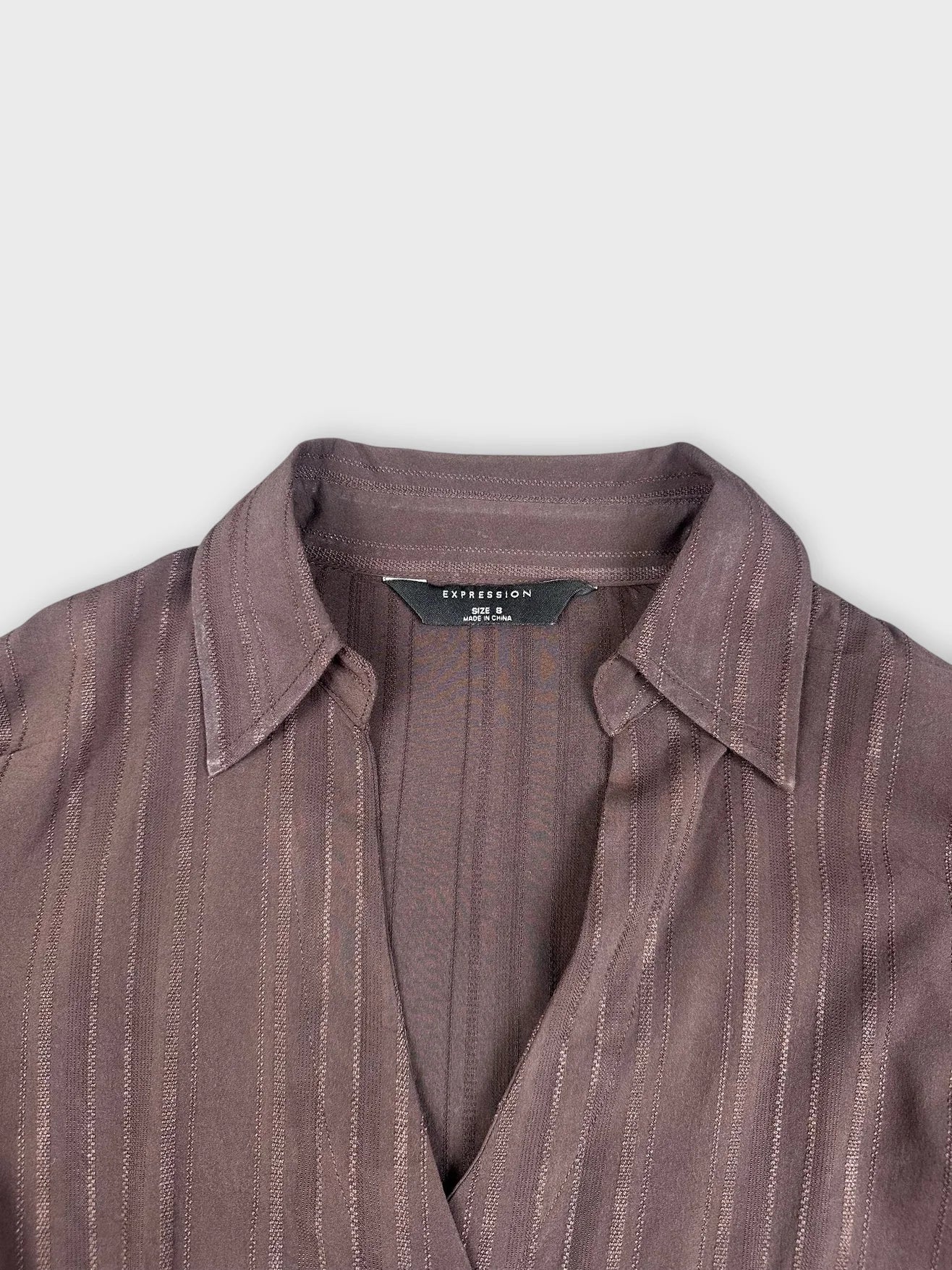 detail view of brown wrap blouse featuring subtle vertical stripes and a classic collar