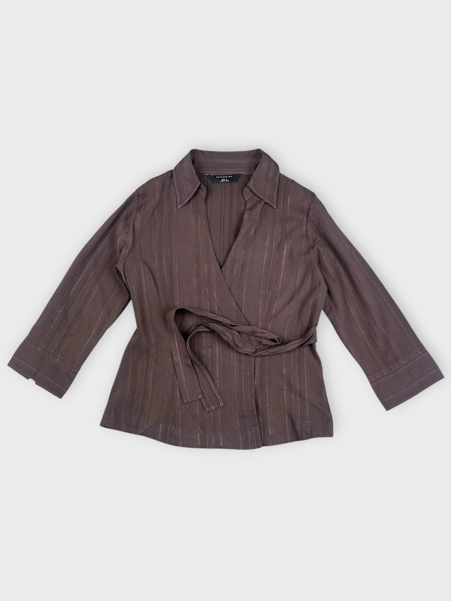 Detail view of a brown wrap blouse with vertical stripes and self-tie belt.
