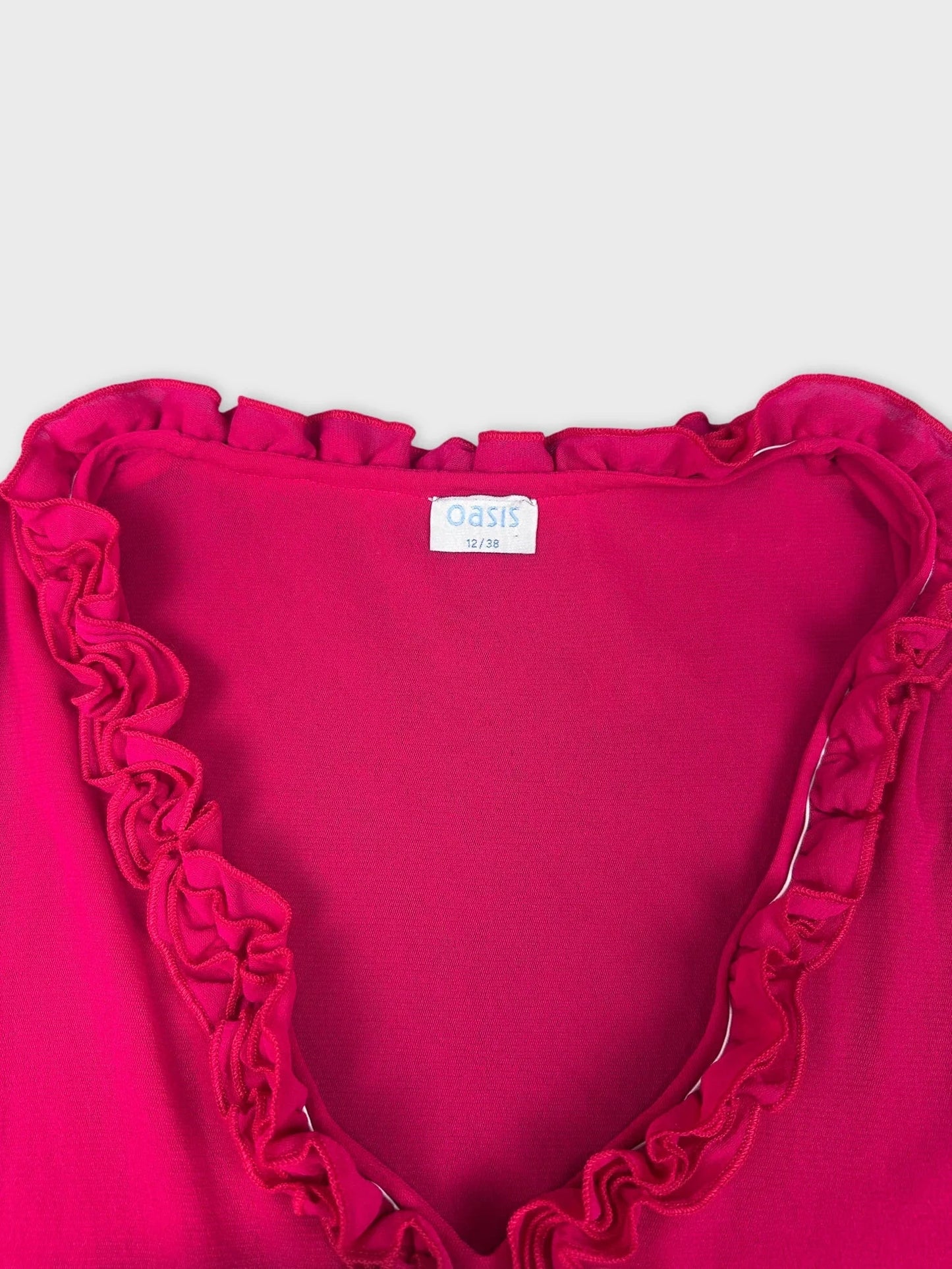 Detail view of a hot pink ruffled tank top highlighting neckline ruffle.