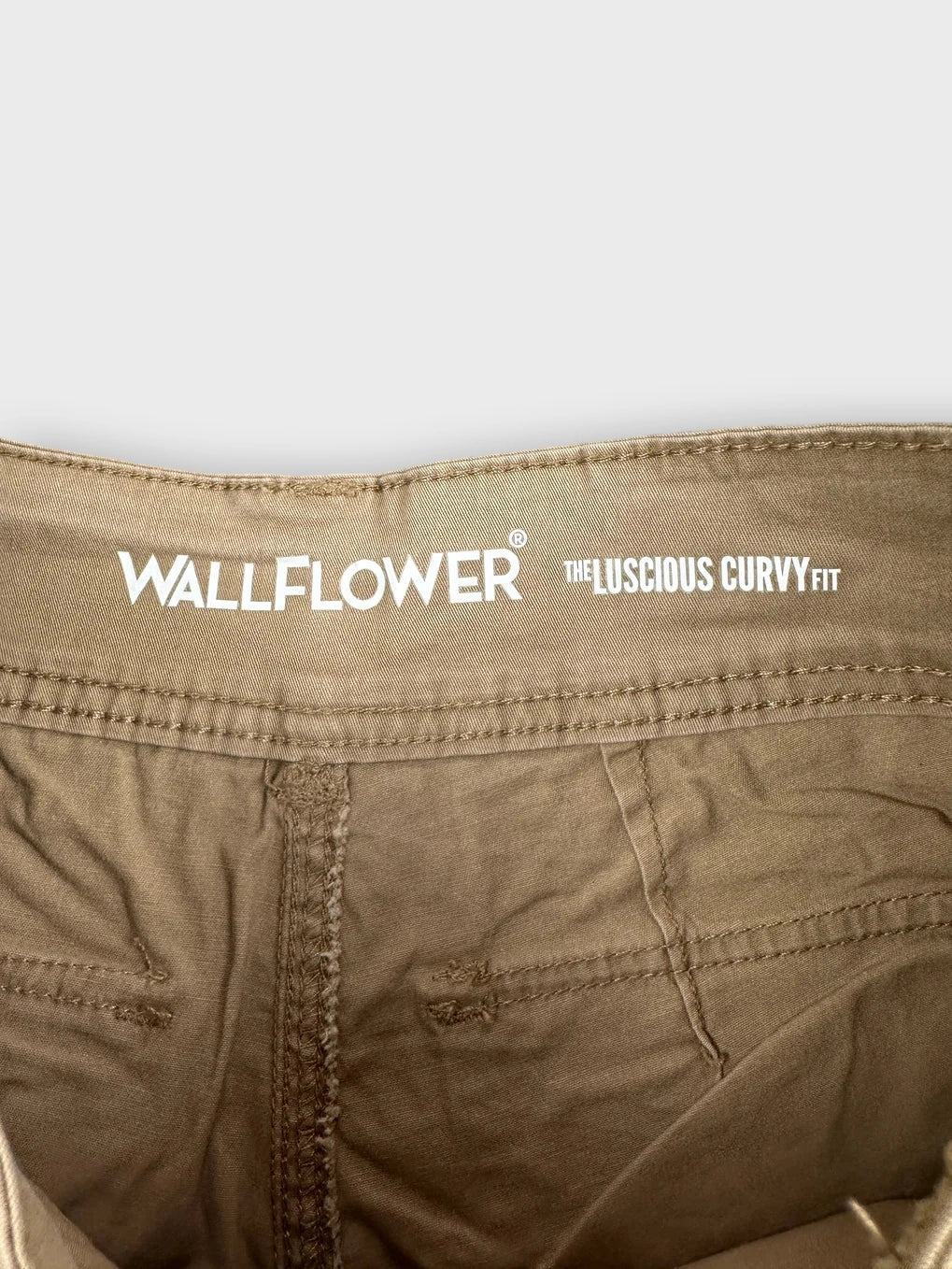 Detail view of khaki mini cargo shorts showing stitching and waistband.
