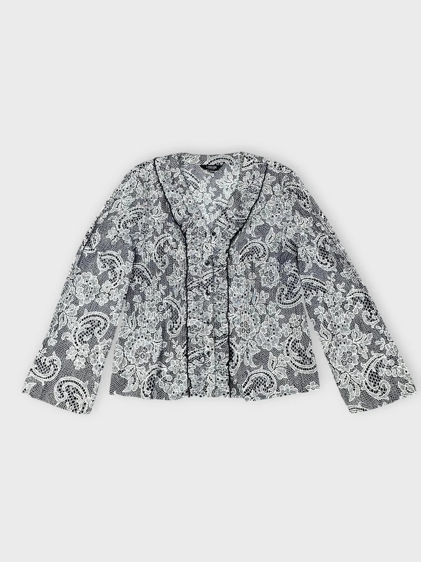 Lace-print button-up blouse in black and white with ruffle trim front view.