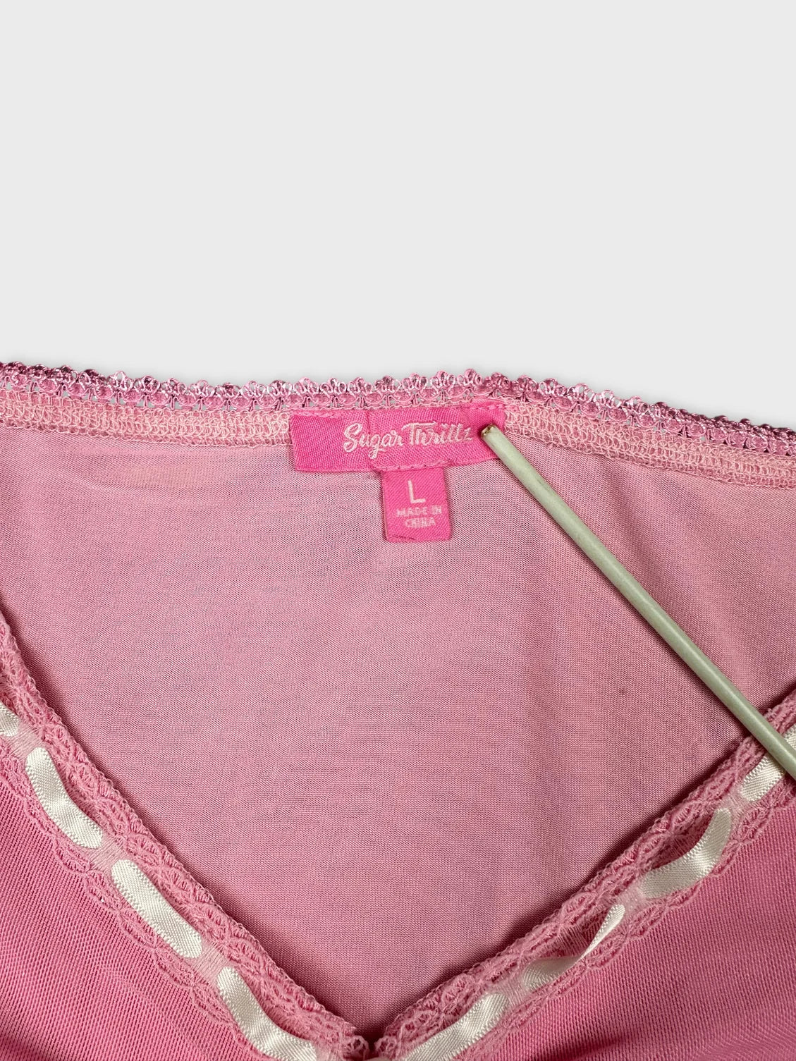 Detail view of pink crop top showcasing lace trim and tie design.