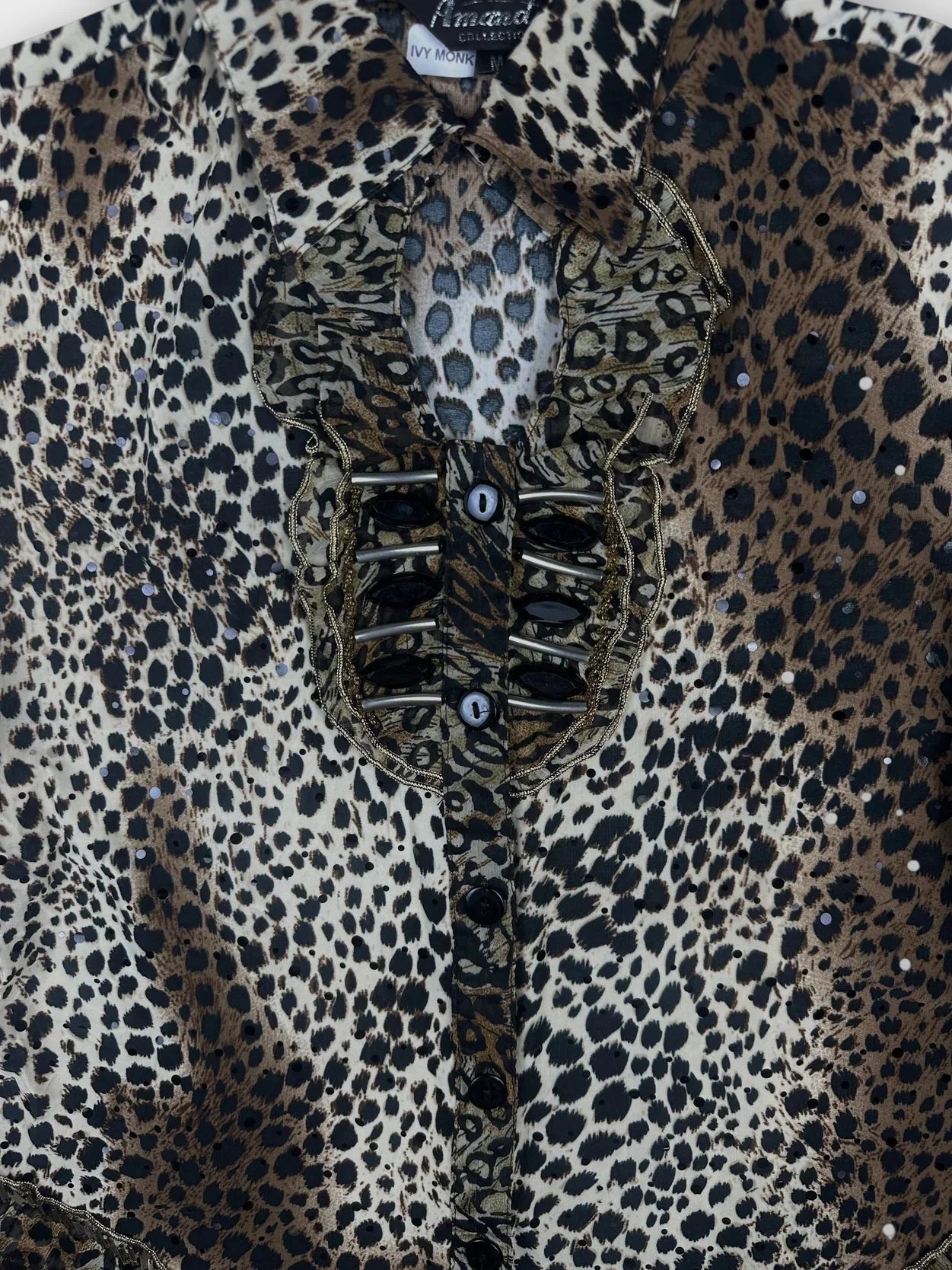 Detail view of leopard print button-up top featuring ruffled trim and decorative buttons.