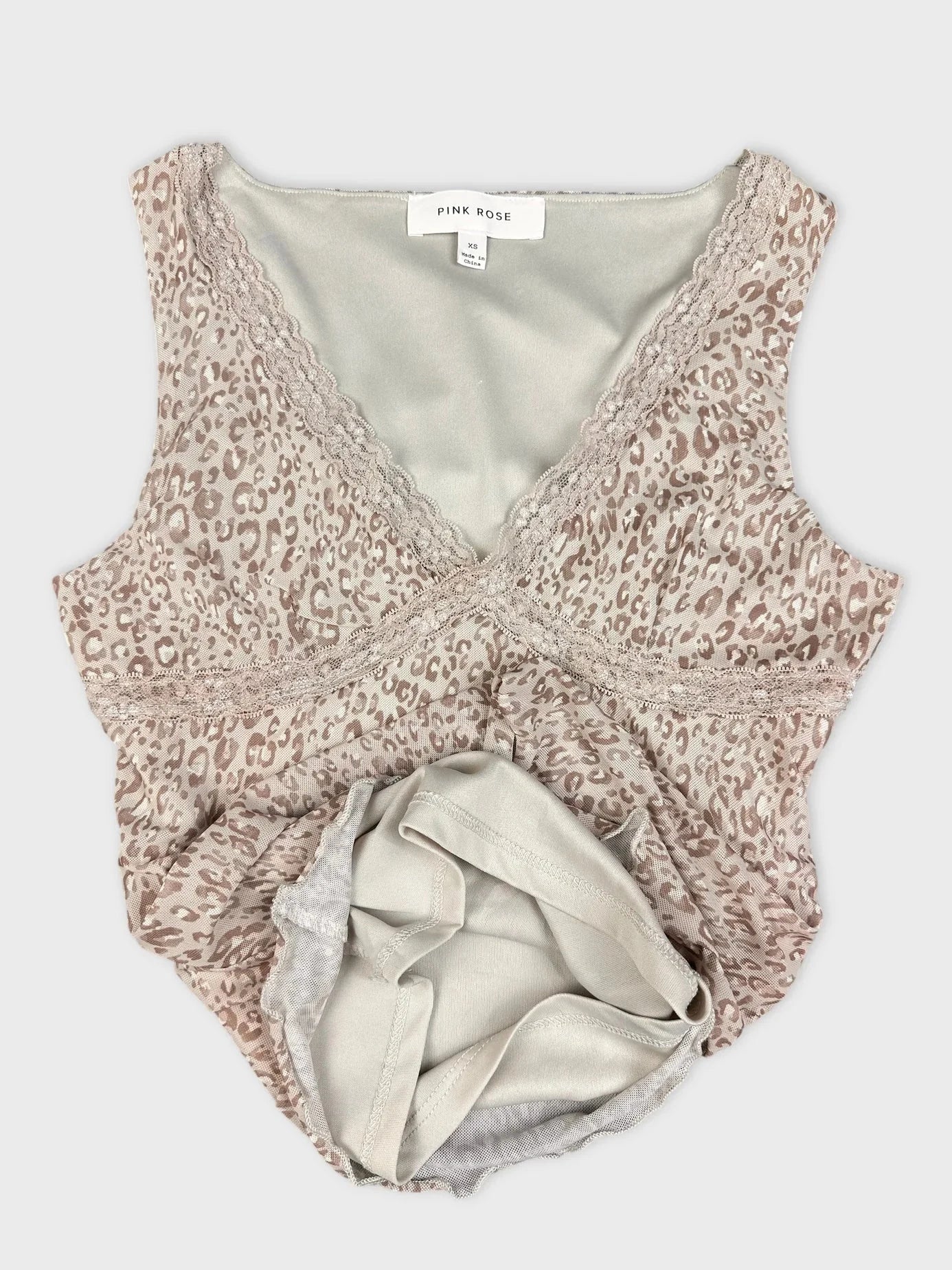 Detail view of a beige leopard print short sleeve top with lace trim.
