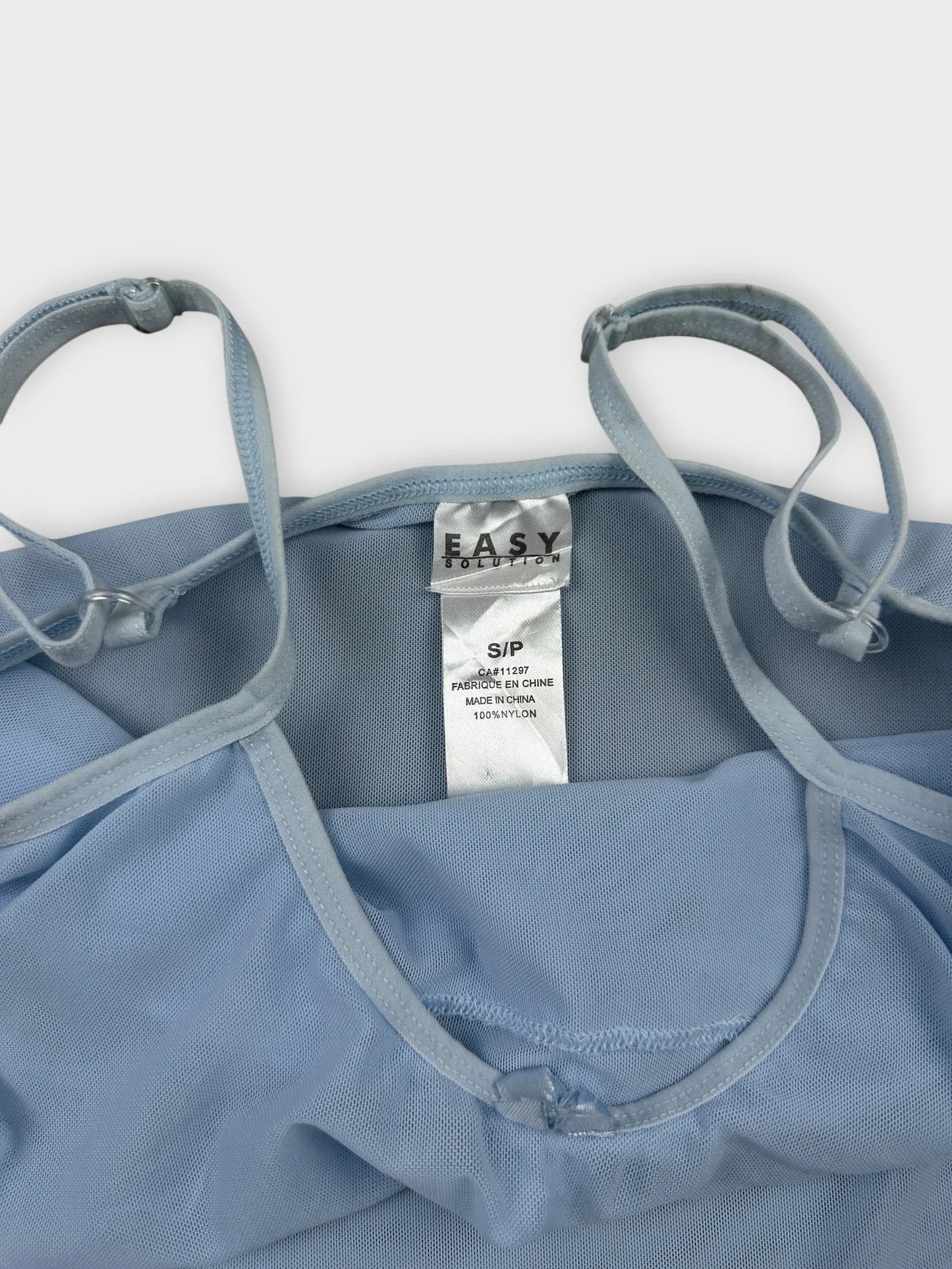 Light blue camisole with ruffle trim detail view, featuring thin straps.