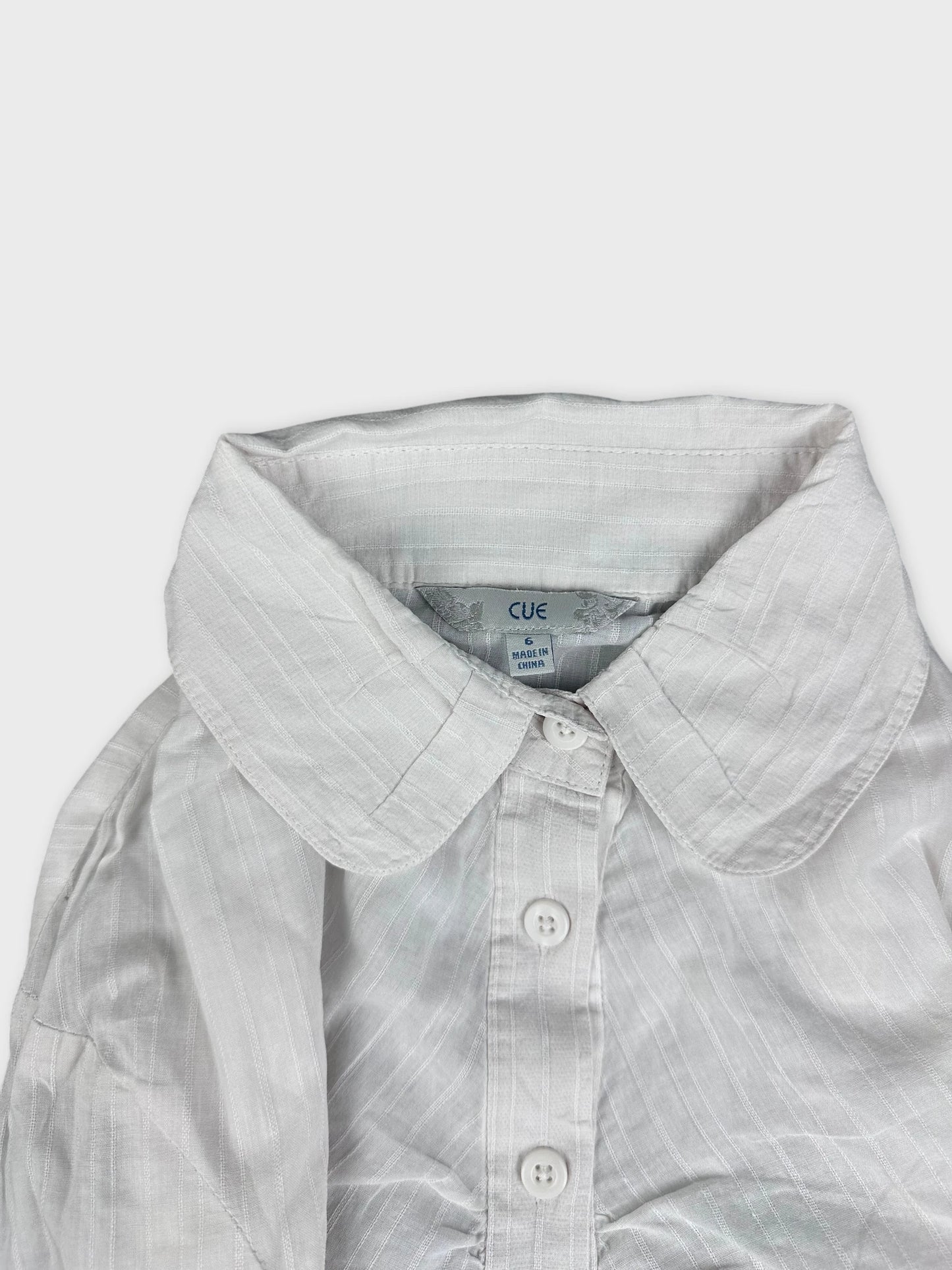 Detail view of a white shirt featuring a classic collar and button placket.