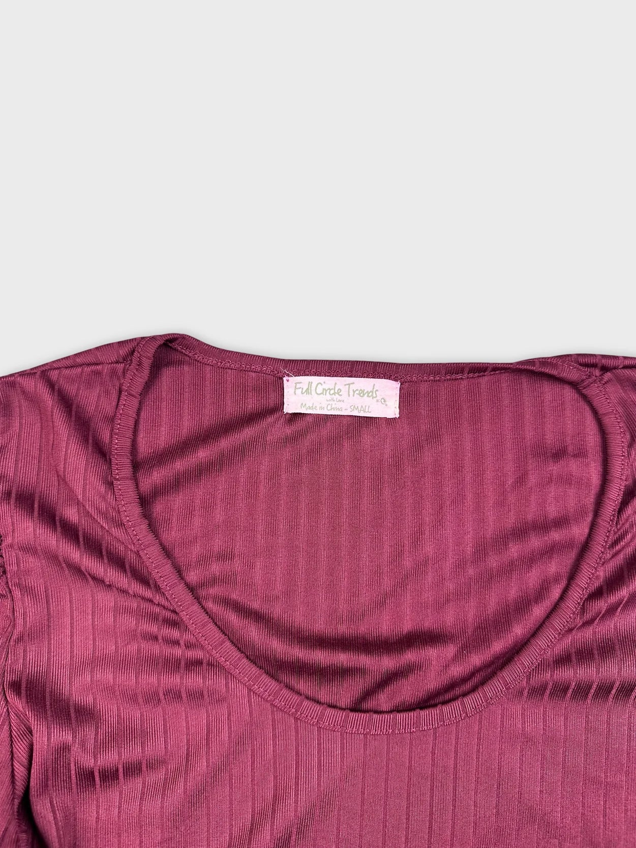 Detail view of maroon ribbed long sleeve top's neckline and texture.